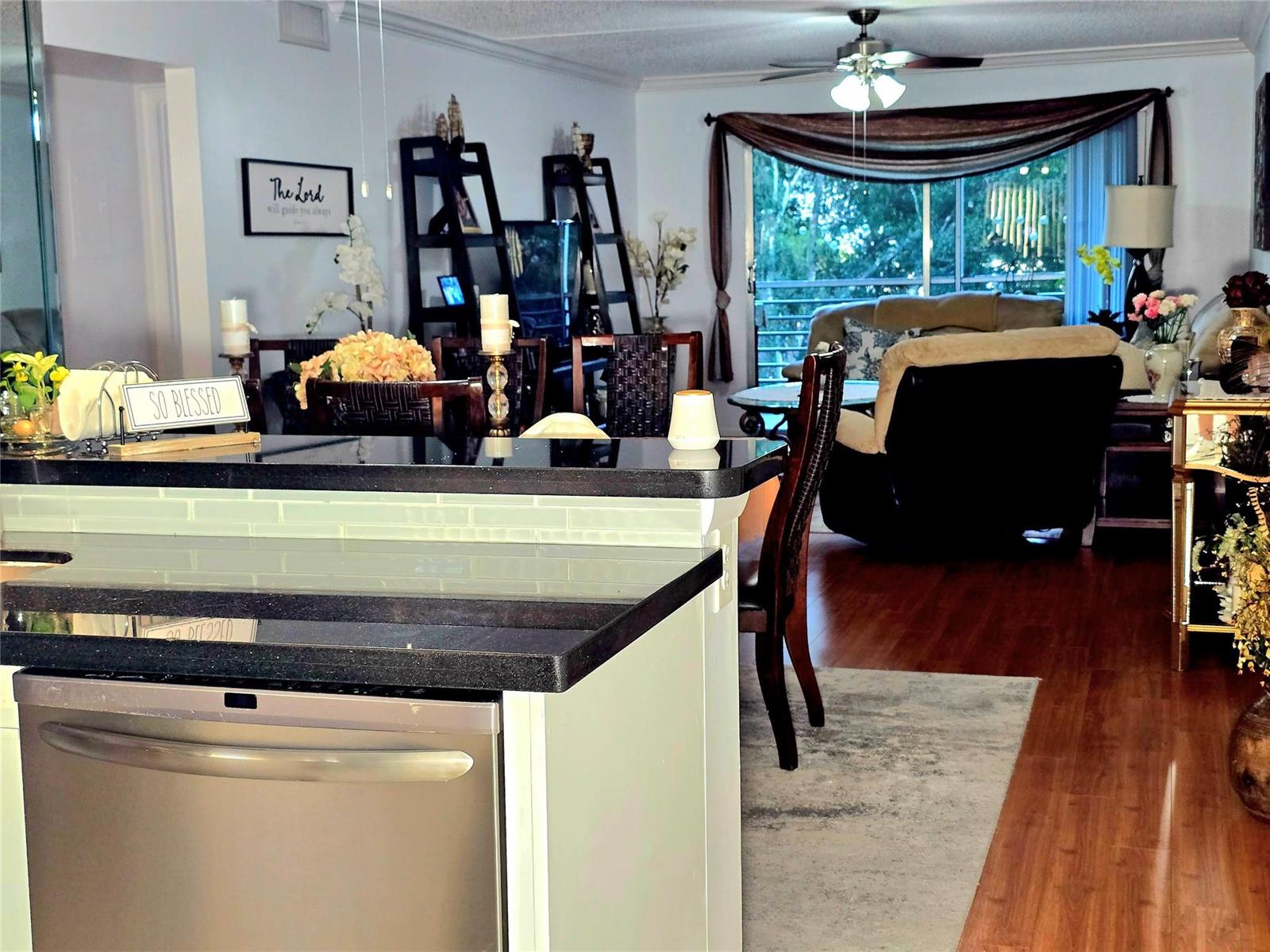 A kitchen island with a black countertop overlooks a dining area and living room — 2002 Granada Drive # K3, Coconut Creek FL 33066, COCONUT CREEK, FL