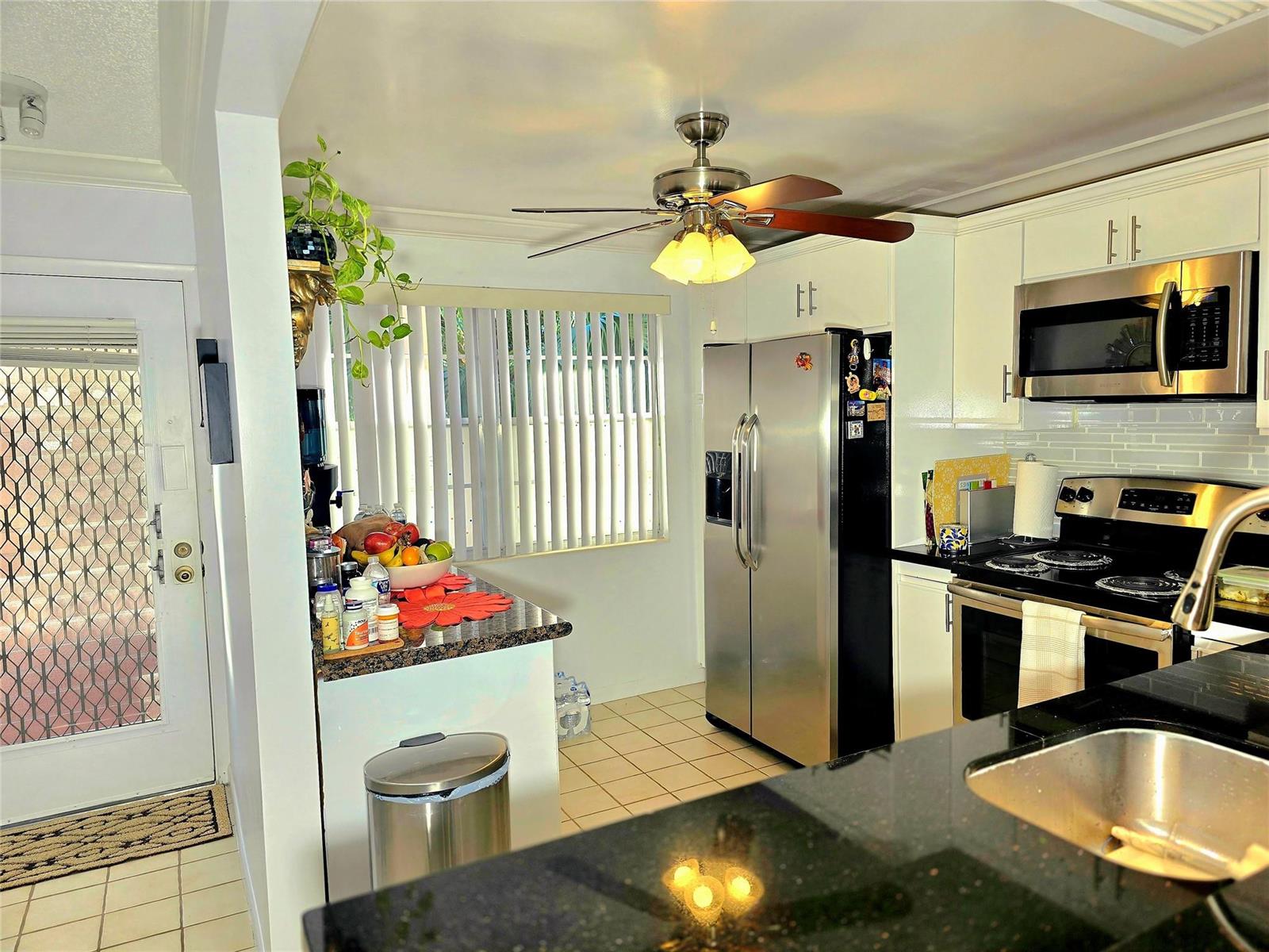 A kitchen features white cabinets, stainless steel appliances, granite countertops, and a ceiling fan — 2002 Granada Drive # K3, Coconut Creek FL 33066, COCONUT CREEK, FL