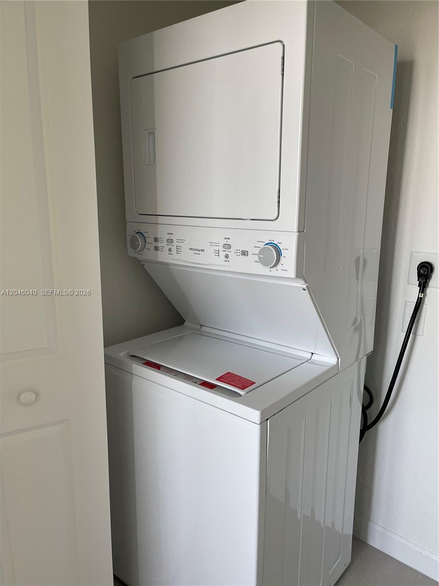 A white Frigidaire stacked washer and dryer unit stands in a small laundry closet — 21447 NE 2nd Pl, Miami FL 33179, MIAMI, FL