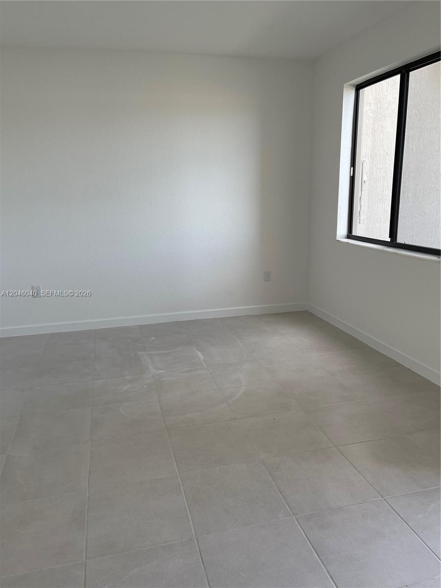 This room features white walls, light-colored tile flooring, and a window with a black frame — 21447 NE 2nd Pl, Miami FL 33179, MIAMI, FL