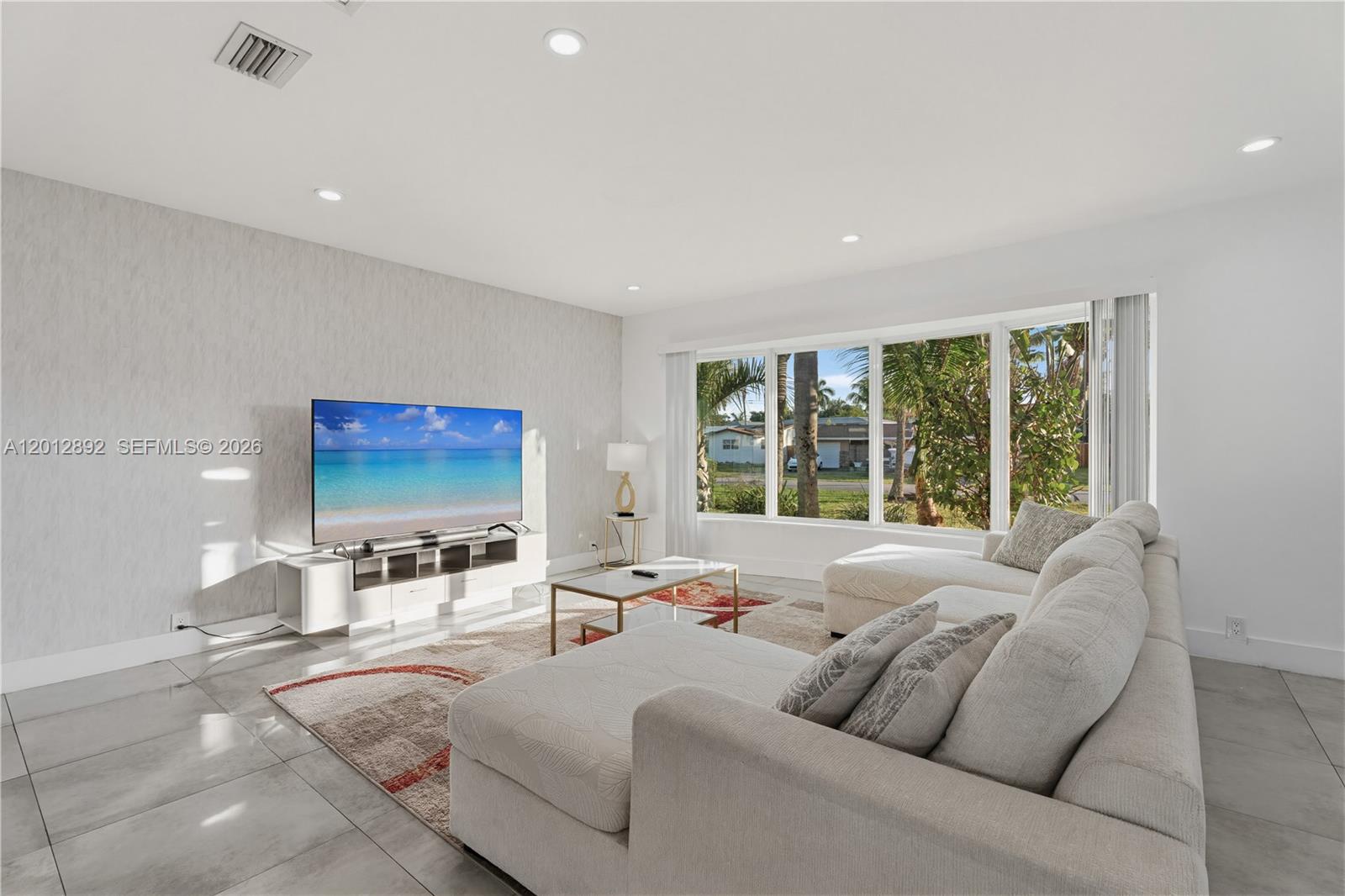 A bright living room features a large sectional sofa, a television, and floor-to-ceiling windows — 632 S Crescent Dr, Hollywood FL 33021, HOLLYWOOD, FL