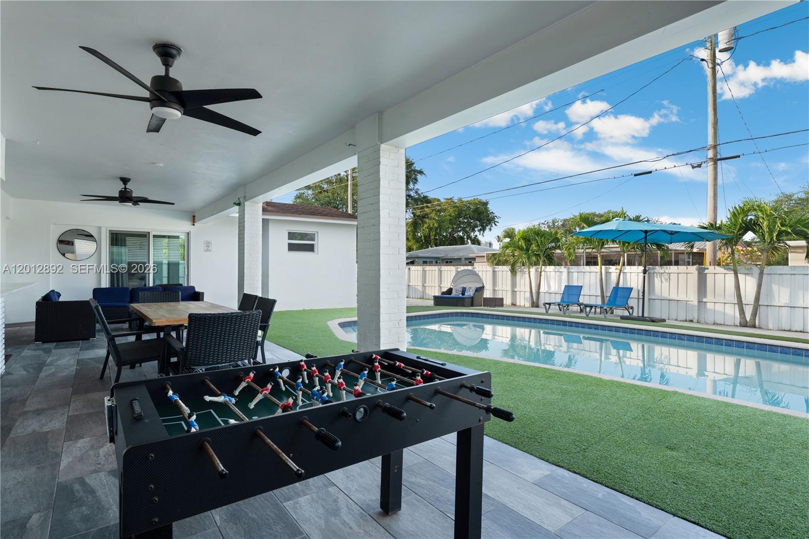 A covered patio features a foosball table, dining area, and a view of a swimming pool — 632 S Crescent Dr, Hollywood FL 33021, HOLLYWOOD, FL