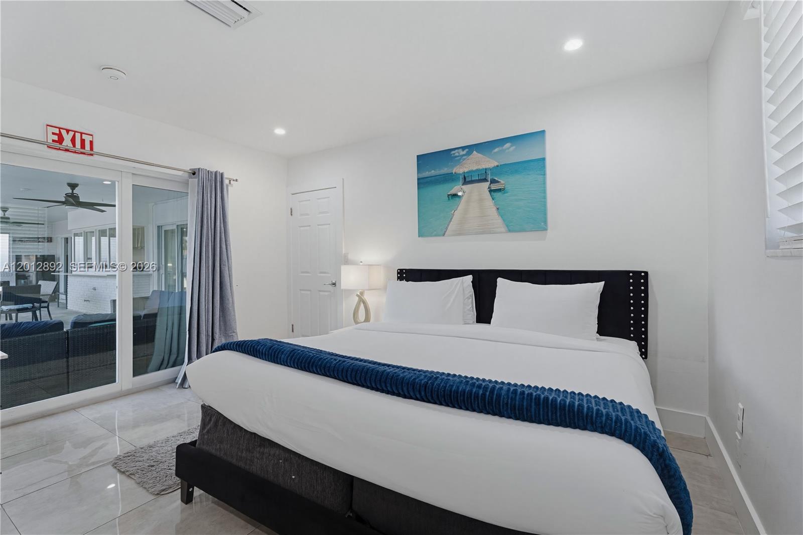 A bedroom features a king bed, a blue throw blanket, and a sliding glass door — 632 S Crescent Dr, Hollywood FL 33021, HOLLYWOOD, FL