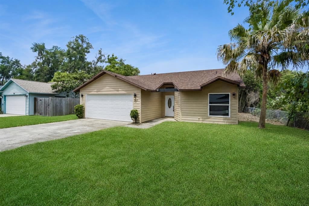 A tan, single-story house with a two-car garage and a front lawn under a blue sky — 761 ROBINHOOD DRIVE, MAITLAND, FL