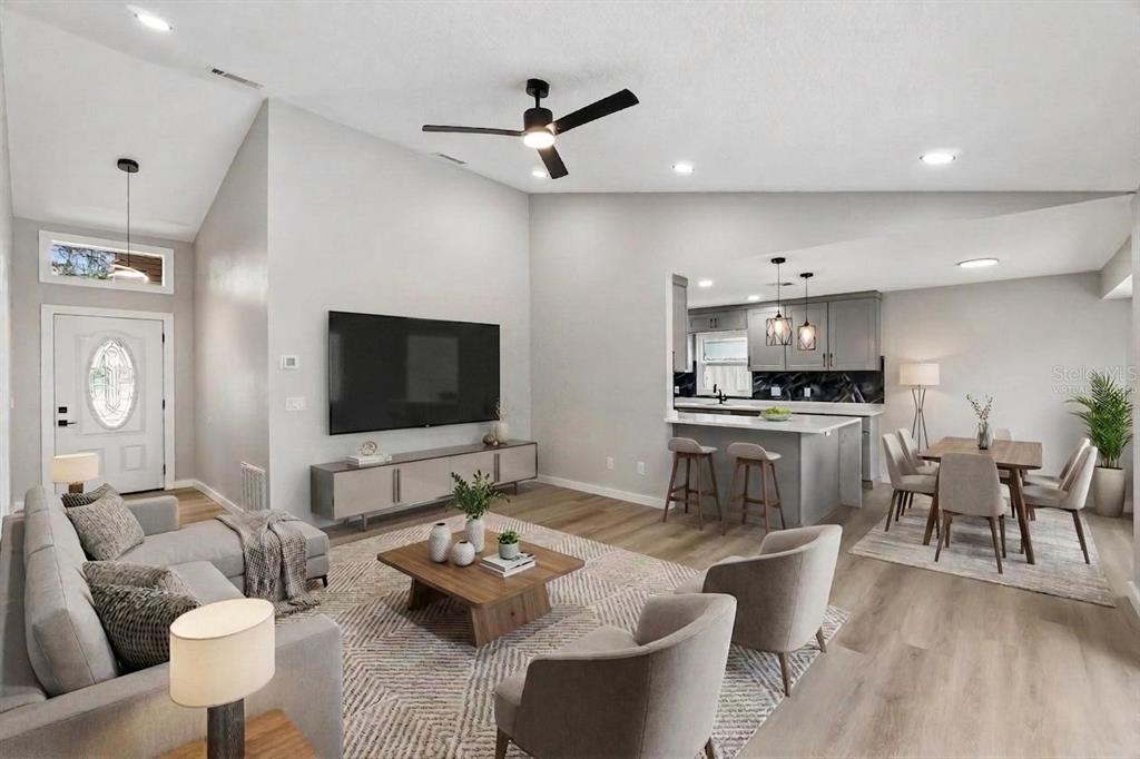 This open-concept living and dining area features vaulted ceilings, light wood flooring, and gray cabinetry — 761 ROBINHOOD DRIVE, MAITLAND, FL