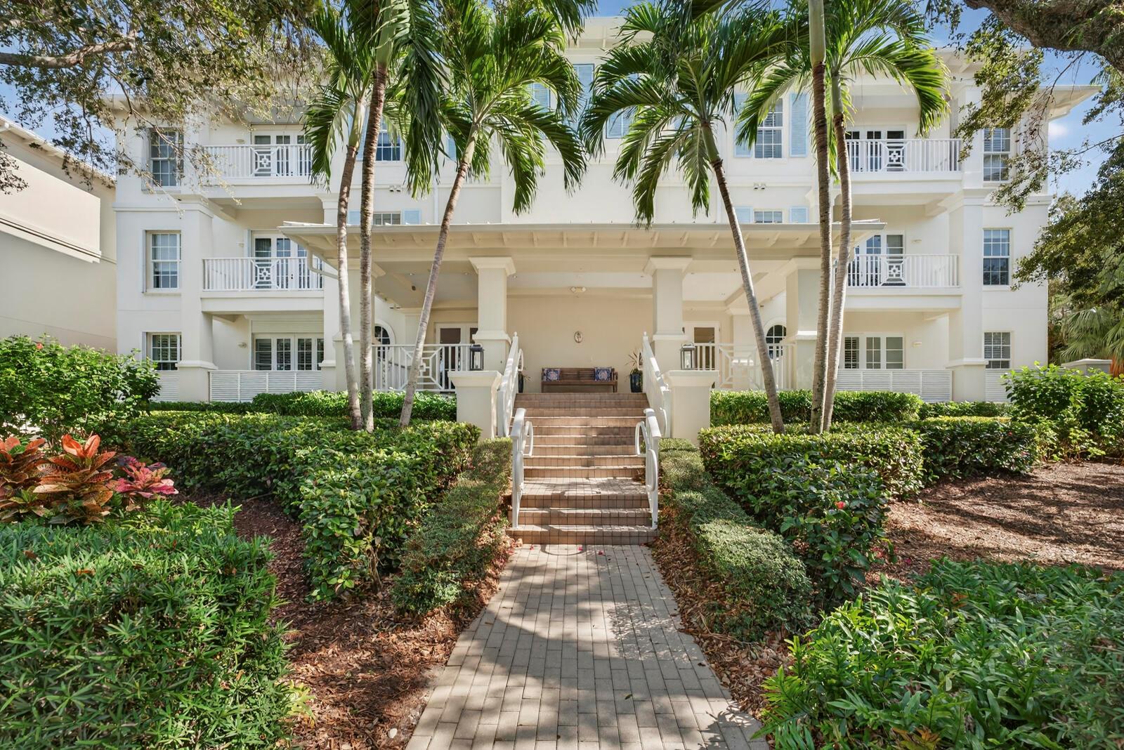 A multi-story white building with a central staircase leading to a covered entrance and palm trees — VERO BEACH, FL