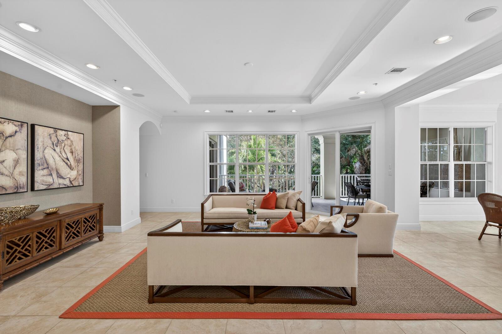 A living room with tile floors, two sofas, a wooden console, and large windows — VERO BEACH, FL