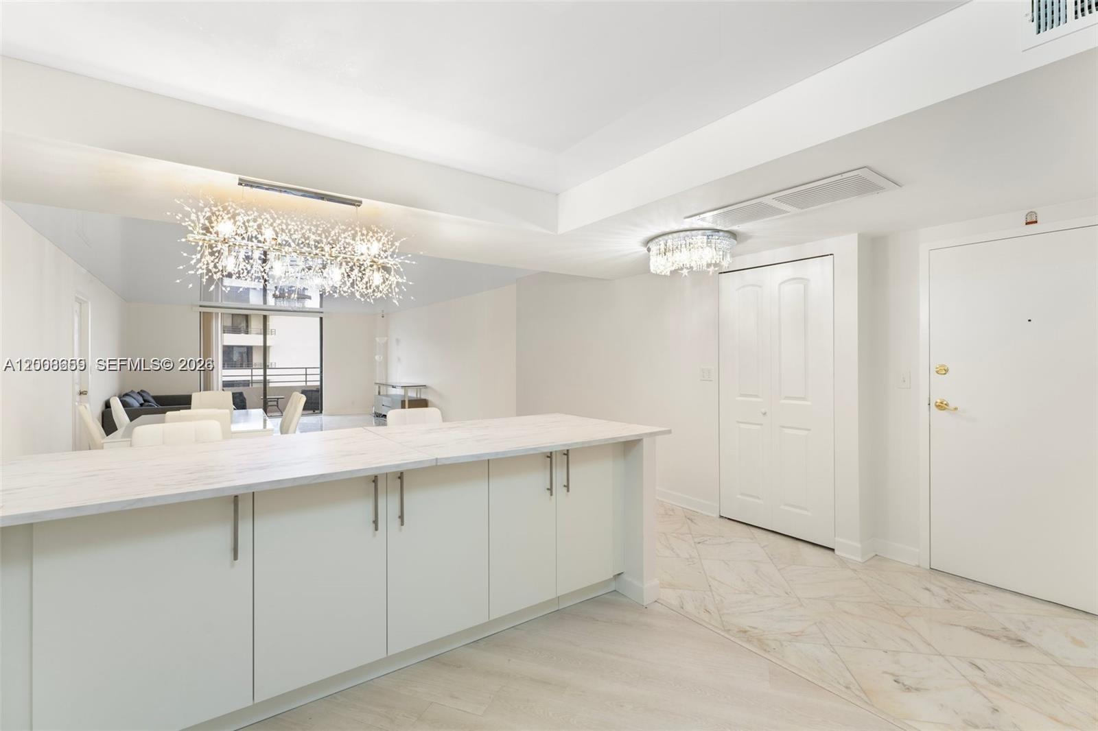 A modern kitchen island with white cabinets and a marble countertop sits in a bright room — 2500 Parkview Dr # 1714, Hallandale Beach FL 33009, HALLANDALE BEACH, FL