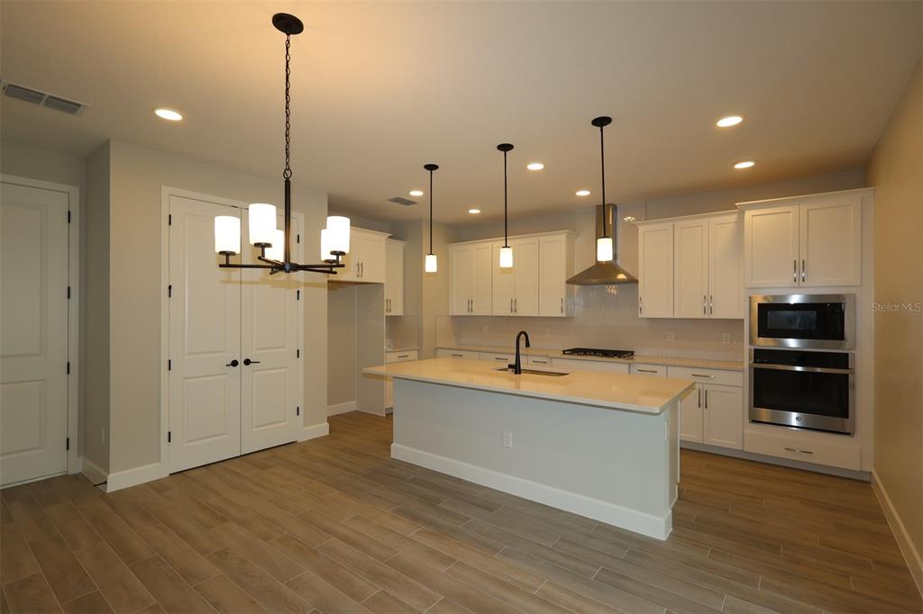 A modern living room features a beige sectional sofa, a round coffee table, and hardwood floors — 12033 ENCORE AT OVATION WAY, WINTER GARDEN, FL