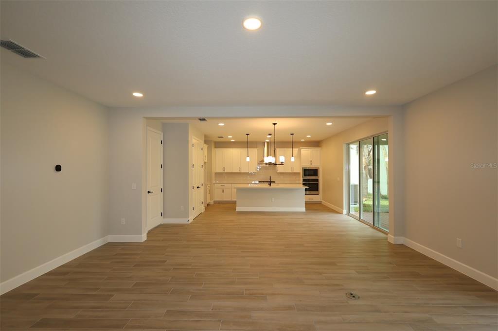 This is a rendering of a living room with a sofa, armchairs, and a television — 12033 ENCORE AT OVATION WAY, WINTER GARDEN, FL