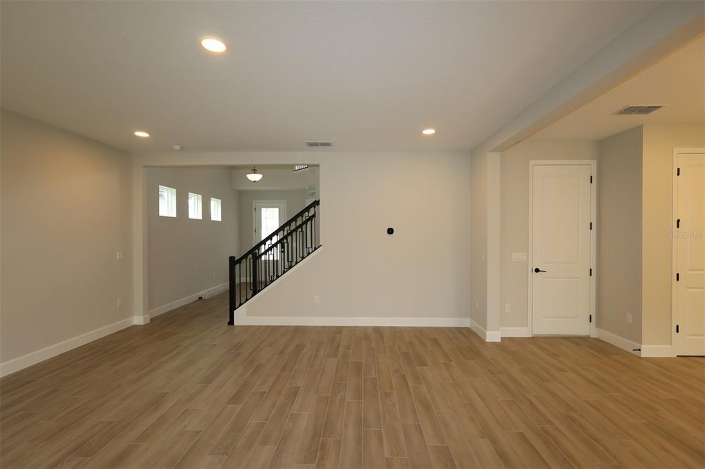 A living room with a beige sofa opens into a dining area and kitchen — 12033 ENCORE AT OVATION WAY, WINTER GARDEN, FL