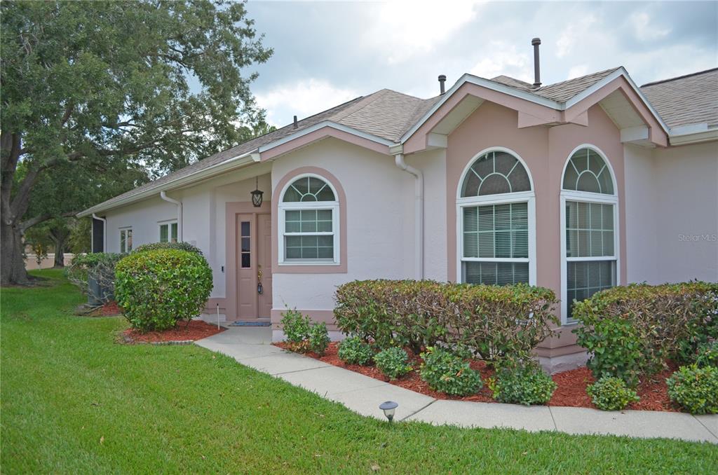 A light-colored house exterior features a front entrance, arched windows, and landscaped garden beds — 11333 PINK BLOSSOM COURT, ORLANDO, FL