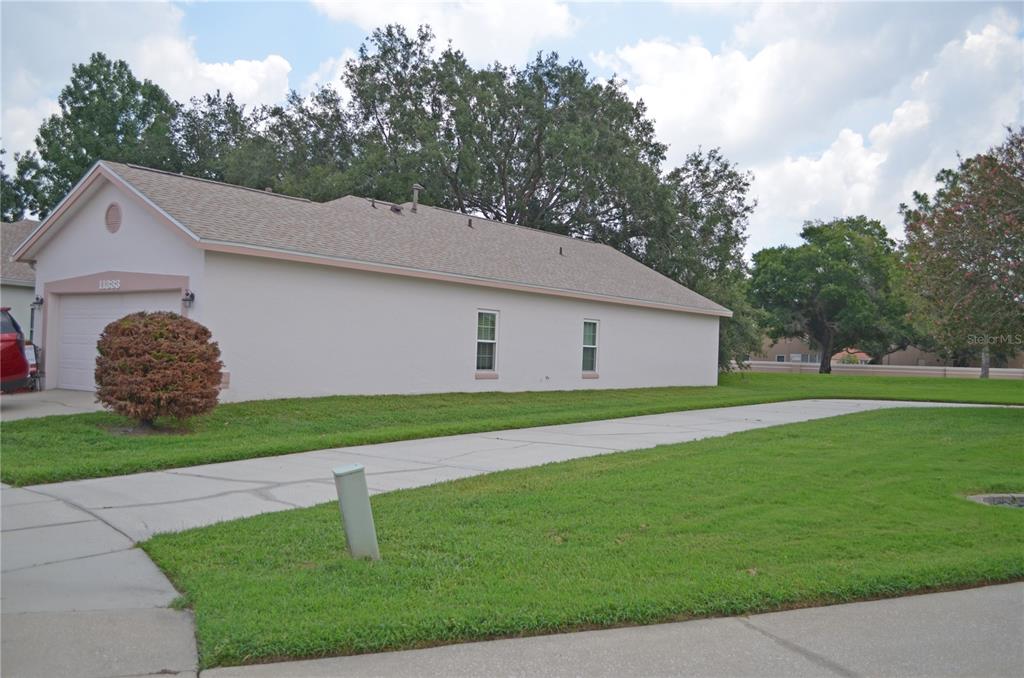 A side view of a single-story house with a beige exterior, garage, and concrete driveway — 11333 PINK BLOSSOM COURT, ORLANDO, FL