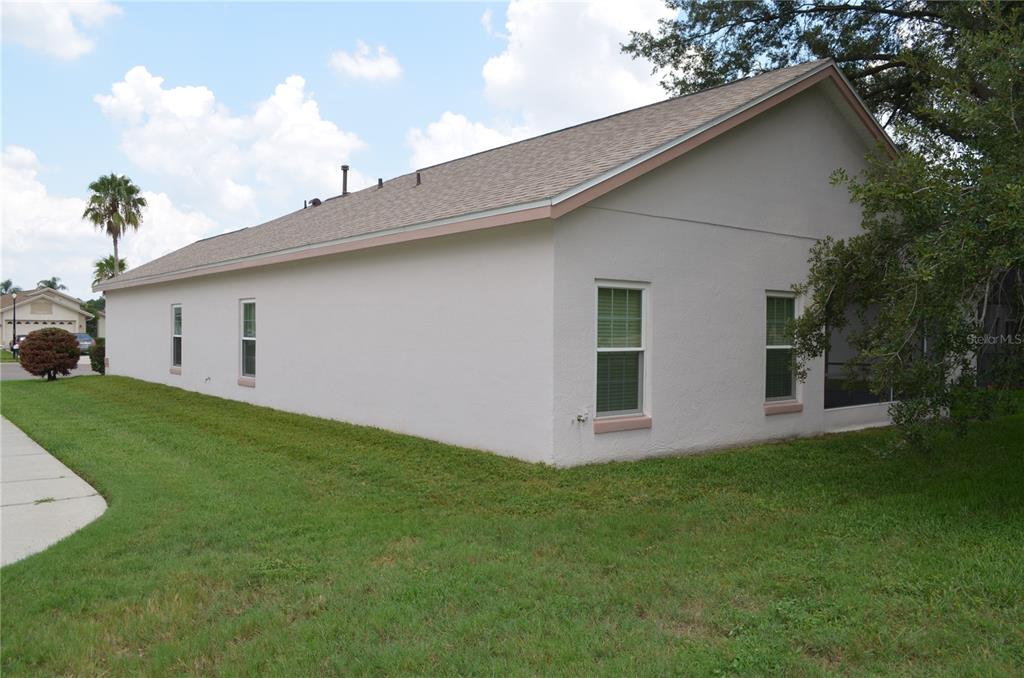 A side view of a light-colored stucco house with a shingled roof and lawn — 11333 PINK BLOSSOM COURT, ORLANDO, FL