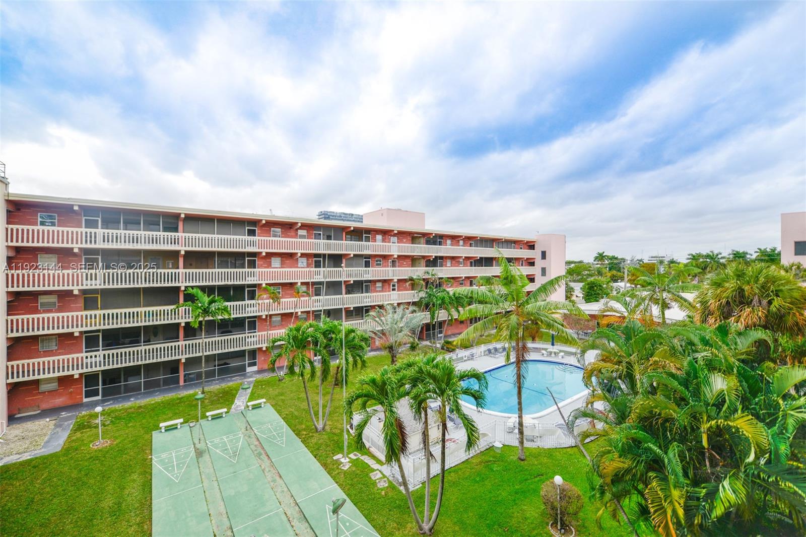 An exterior view of a multi-story apartment building with a pool and shuffleboard courts — 200 NE 12th Ave # 6D, Hallandale Beach FL 33009, HALLANDALE BEACH, FL