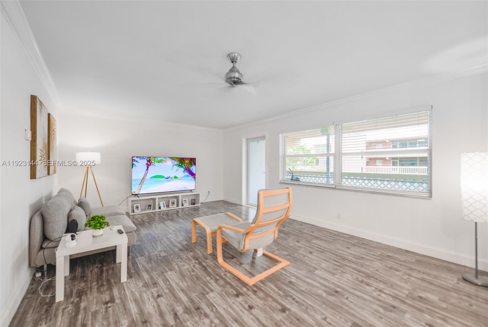 A living room features gray wood-look flooring, a gray sofa, and a modern lounge chair — 200 NE 12th Ave # 6D, Hallandale Beach FL 33009, HALLANDALE BEACH, FL