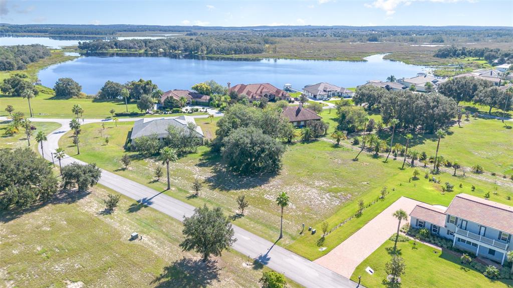 An aerial view shows a residential neighborhood with houses, a lake, and grassy lots — 7434 JASMINE STREET, GROVELAND, FL