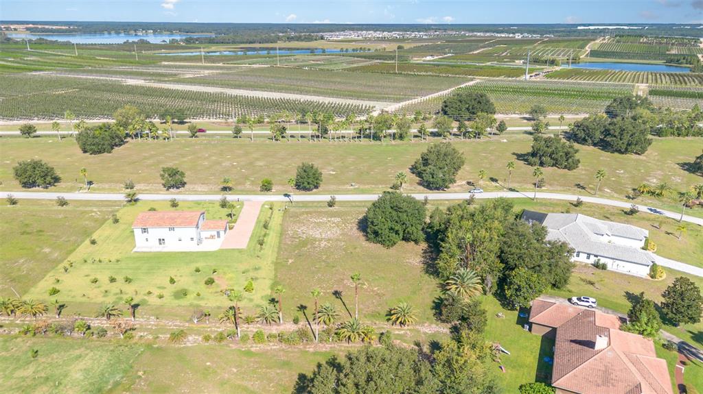 An aerial view shows three houses surrounded by large grassy lots and agricultural fields — 7434 JASMINE STREET, GROVELAND, FL