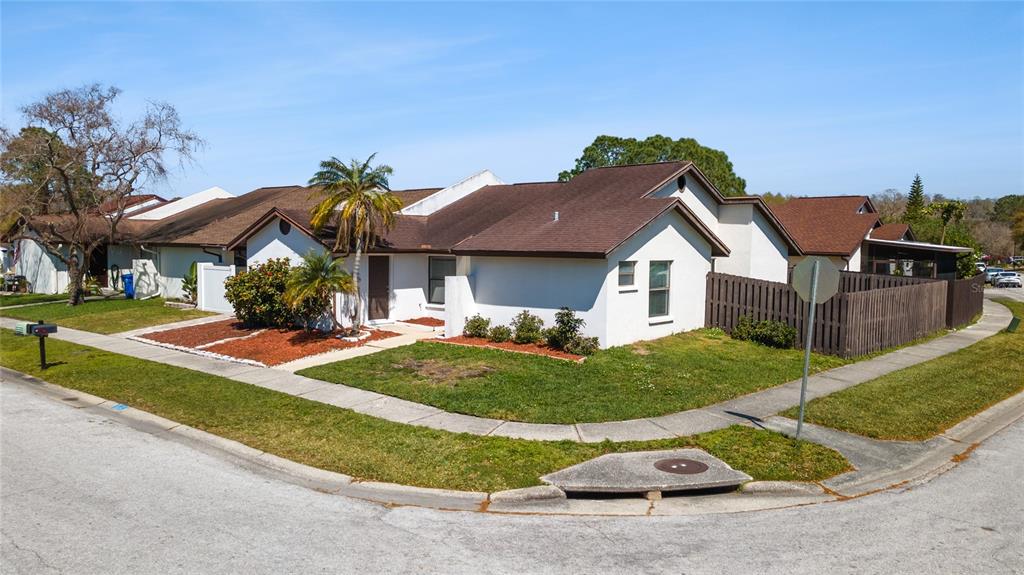 An exterior view of a single-story white house on a corner lot with brown roofing — 5201 BELLEFIELD DRIVE, TAMPA, FL
