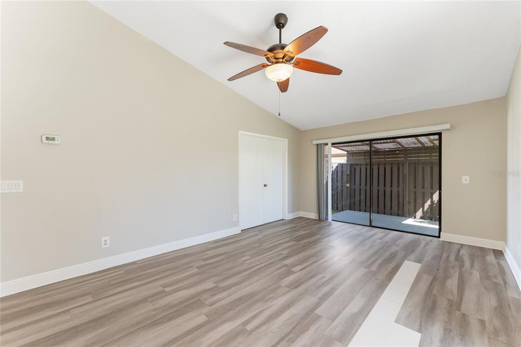 An empty room with light-colored walls, wood-look flooring, a ceiling fan, and sliding glass doors — 5201 BELLEFIELD DRIVE, TAMPA, FL
