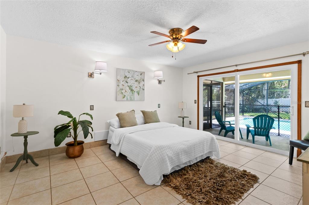 A bedroom with tile floors, a ceiling fan, a bed, and sliding glass doors to a pool — 4209 LORI LOOP, WINTER SPRINGS, FL