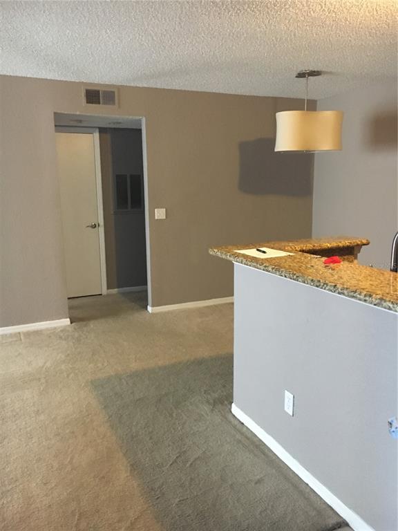 A view of a carpeted living area with a granite-topped breakfast bar and pendant lighting — 5112 CONROY ROAD UNIT 315, ORLANDO, FL