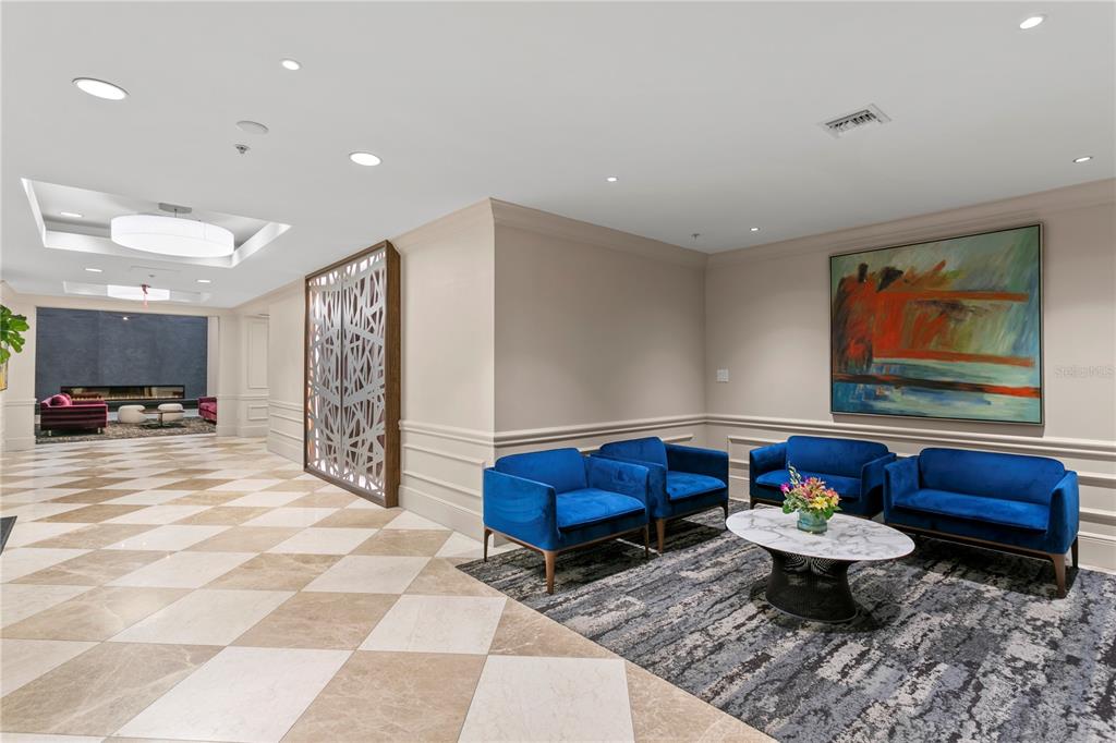 A lobby features a checkered tile floor, blue velvet chairs, and a large abstract painting — 450 KNIGHTS RUN AVENUE UNIT 1208, TAMPA, FL