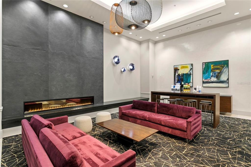 A modern lounge features two velvet sofas, a fireplace, and a high-top table — 450 KNIGHTS RUN AVENUE UNIT 1208, TAMPA, FL