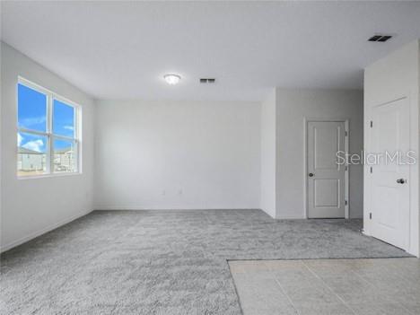 A carpeted room features white walls, a glass door, and a window with exterior views — 130 MANDOVI ST, DAVENPORT, FL