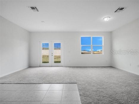 A room with a kitchenette, gray tile flooring, carpeted living area, and glass patio doors — 130 MANDOVI ST, DAVENPORT, FL