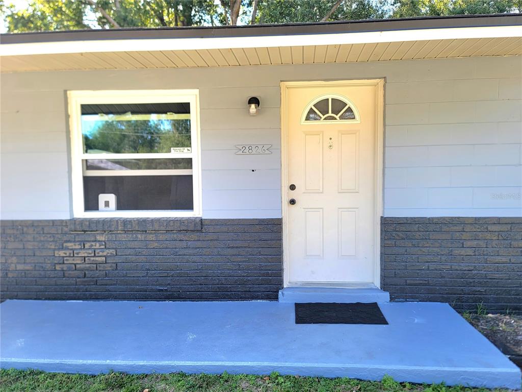 The exterior of a house features a light blue wall, a white door, and a window — 2826 NE 18TH COURT, OCALA, FL