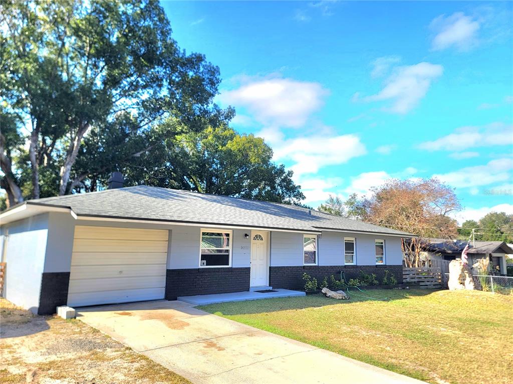 A single-story house with a white garage, grey siding, and a dark brick base — 2826 NE 18TH COURT, OCALA, FL