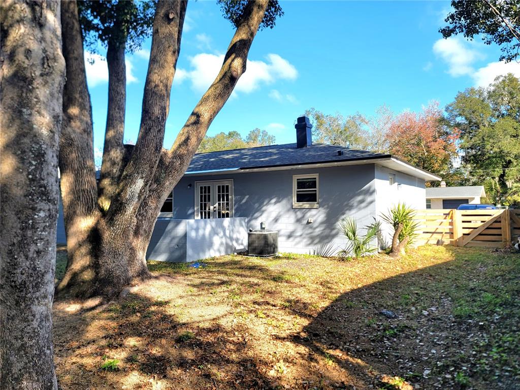A light blue house exterior features a chimney, French doors, and a central air unit — 2826 NE 18TH COURT, OCALA, FL