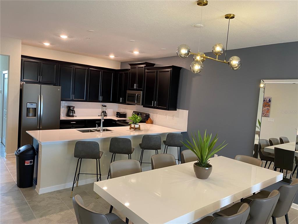 A kitchen with black cabinets, white countertops, and a dining area with a white table — 1149 DROP LANE UNIT 704, DAVENPORT, FL