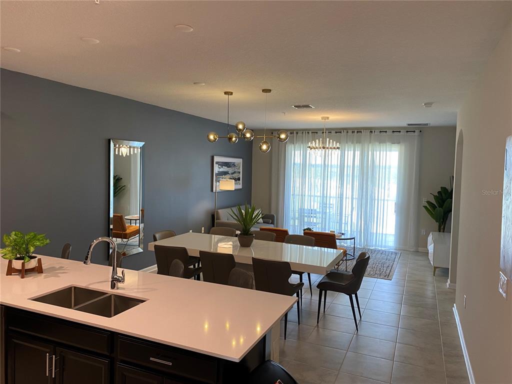 A kitchen island overlooks a dining area and living space with a large sliding glass door — 1149 DROP LANE UNIT 704, DAVENPORT, FL