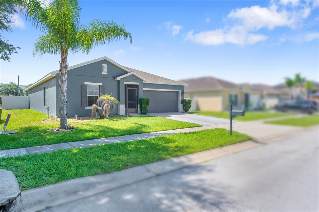 A single-story gray house with a palm tree, a two-car garage, and a front lawn — 524 HAINES TRAIL, WINTER HAVEN, FL