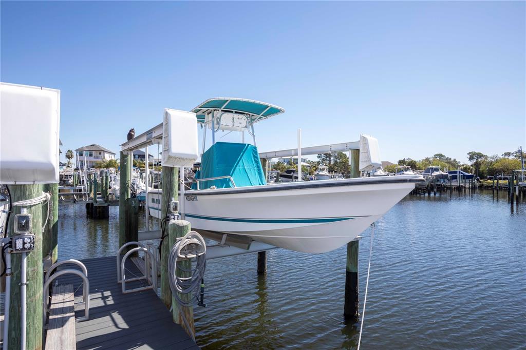 A white motorboat sits on a boat lift at a wooden dock — 5712 BISCAYNE COURT UNIT 101, NEW PORT RICHEY, FL