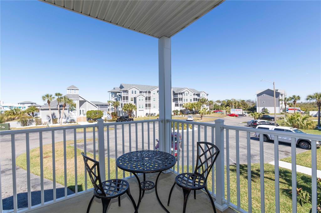 A balcony with a small metal table and two chairs overlooks a parking lot — 5712 BISCAYNE COURT UNIT 101, NEW PORT RICHEY, FL