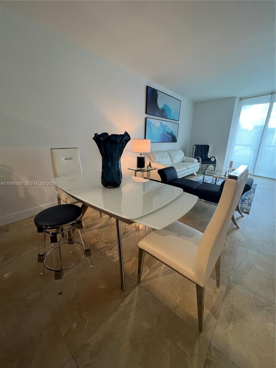 A dining area with a white table and chairs sits in front of a living room — 495 Brickell Ave # 2707, Miami FL 33131, MIAMI, FL