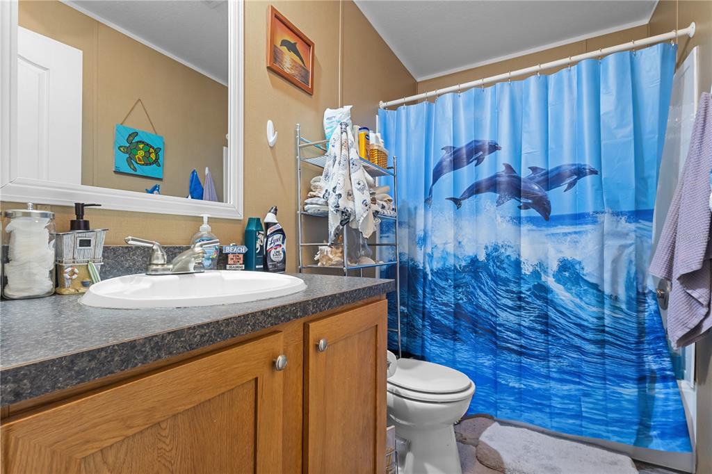 A bathroom features a wood vanity, a sink, and a shower curtain with dolphins — 1650 W LYMAN HENDRY ROAD UNIT 1, PERRY, FL