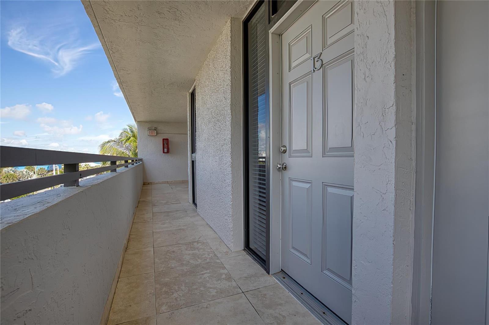 An exterior balcony with tiled flooring leads to a gray door marked with the number 15 — 520 N Ocean Boulevard # 13, Pompano Beach FL 33062, POMPANO BEACH, FL
