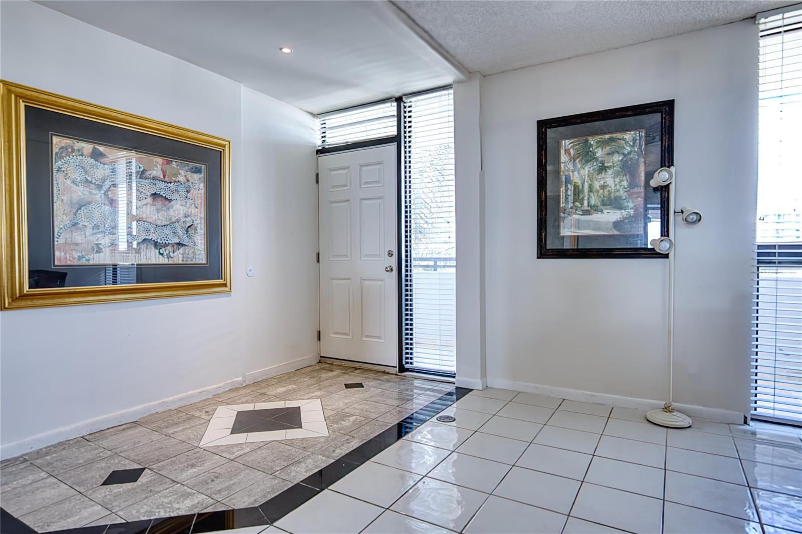 An entryway features a white door, tiled flooring with black accents, and two framed artworks — 520 N Ocean Boulevard # 13, Pompano Beach FL 33062, POMPANO BEACH, FL