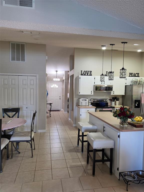 A kitchen with white cabinets and a breakfast bar opens into a dining area — 2824 SUNSET RIDGE ST, DELTONA, FL