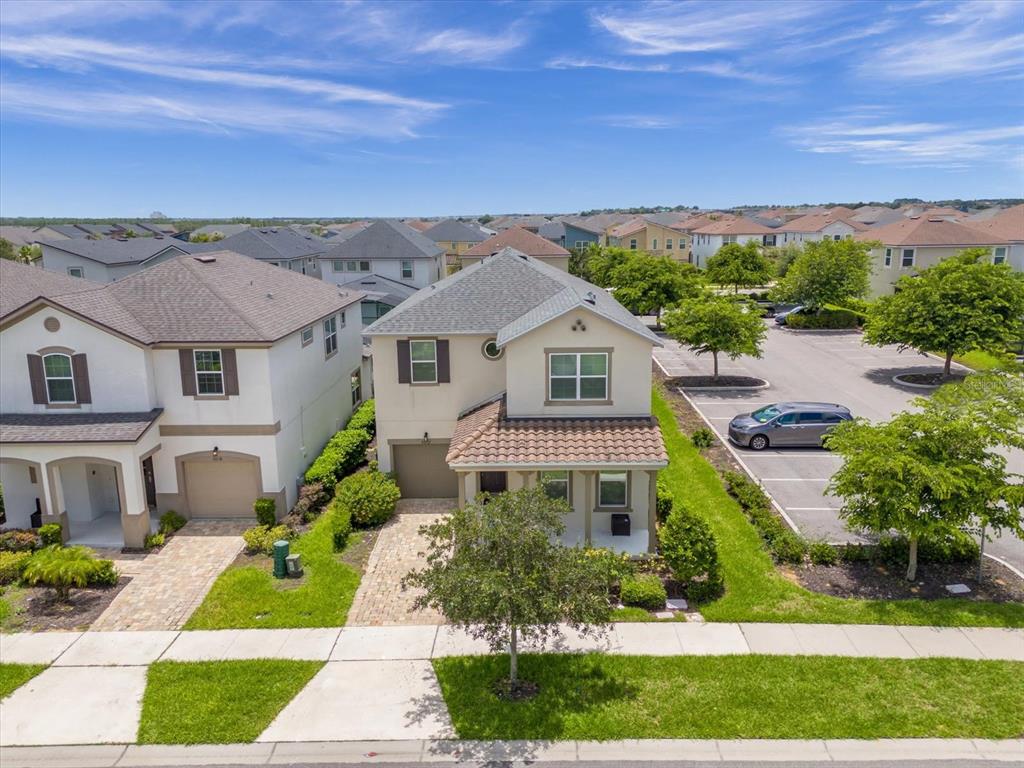 An aerial view shows a two-story suburban house with a paved driveway and adjacent parking — 9012 EGRET MILLS TERRACE, KISSIMMEE, FL