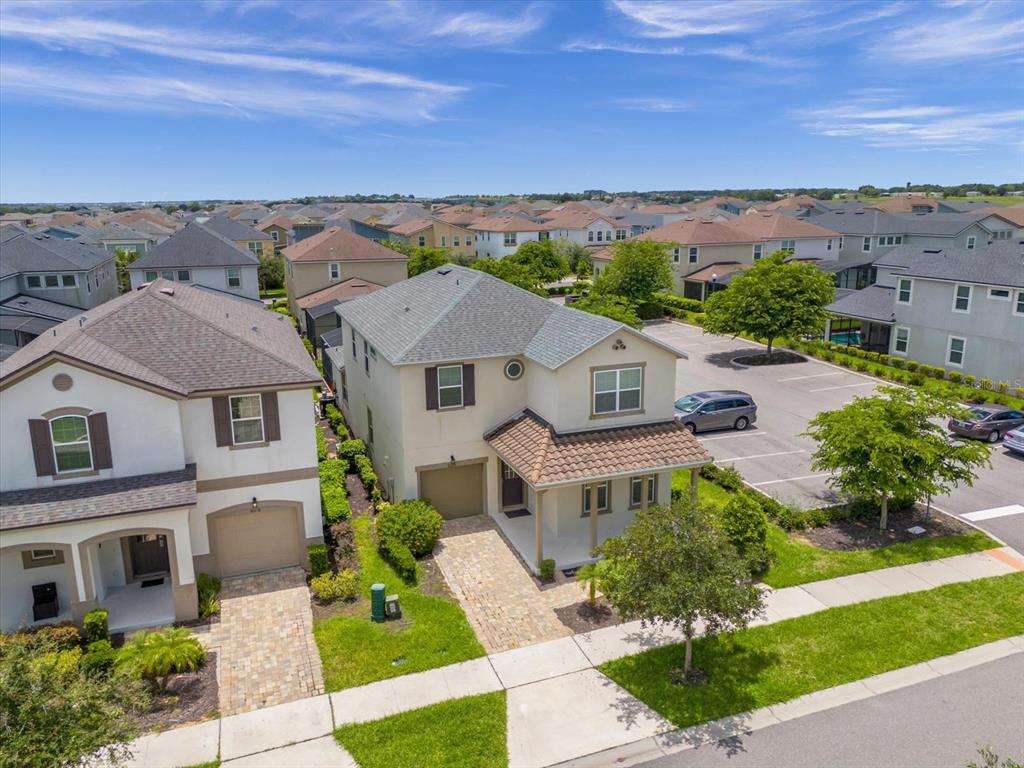 An aerial view shows two suburban houses with paved driveways and a nearby parking lot — 9012 EGRET MILLS TERRACE, KISSIMMEE, FL