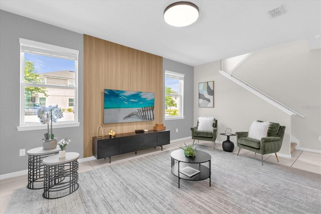A living room features a wood-paneled accent wall, a television, and two green armchairs — 9012 EGRET MILLS TERRACE, KISSIMMEE, FL