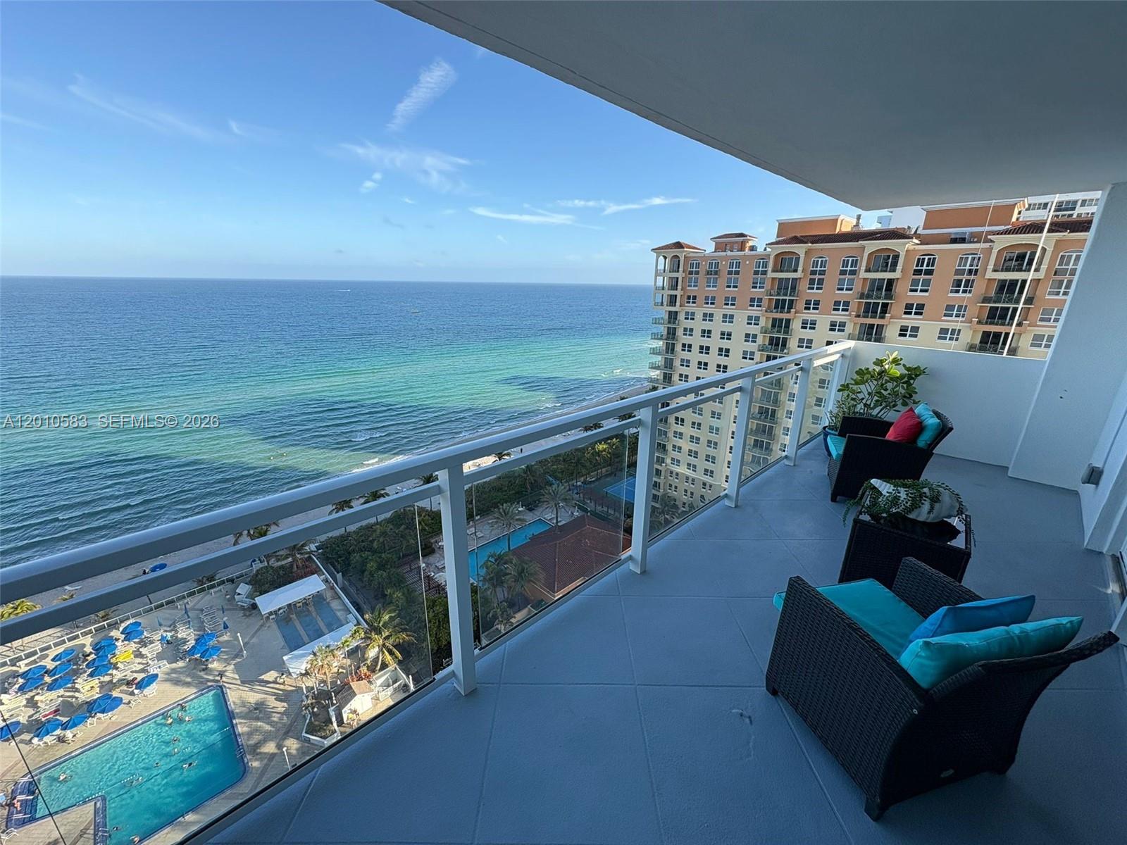 A balcony with patio furniture overlooks the ocean and a swimming pool below — 2030 S Ocean Dr # 1812, Hallandale Beach FL 33009, HALLANDALE BEACH, FL
