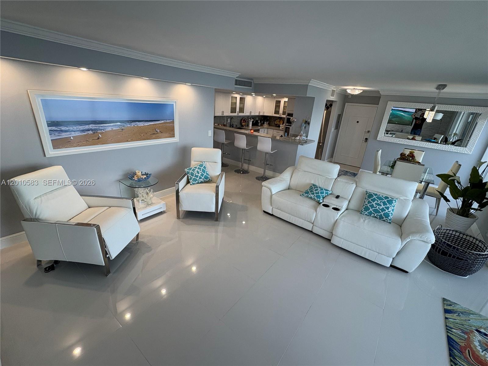 A living room features white leather furniture, a kitchen breakfast bar, and a large beach print — 2030 S Ocean Dr # 1812, Hallandale Beach FL 33009, HALLANDALE BEACH, FL
