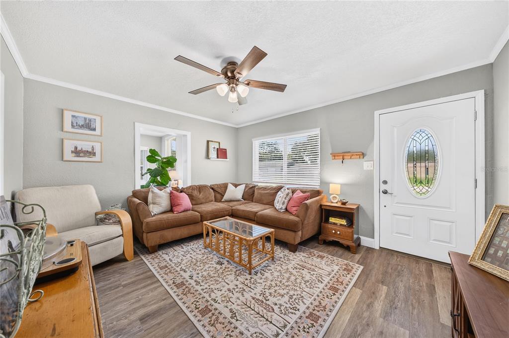 A living room features a brown sectional sofa, a patterned rug, and a front door — 915 DOWD AVENUE, ORLANDO, FL