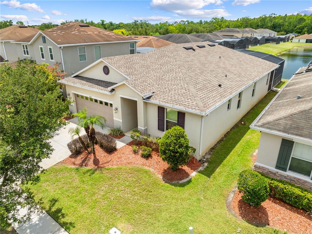 An aerial view shows a single-story suburban house with a tan exterior and shingled roof — 4704 RUBY RED LANE, KISSIMMEE, FL